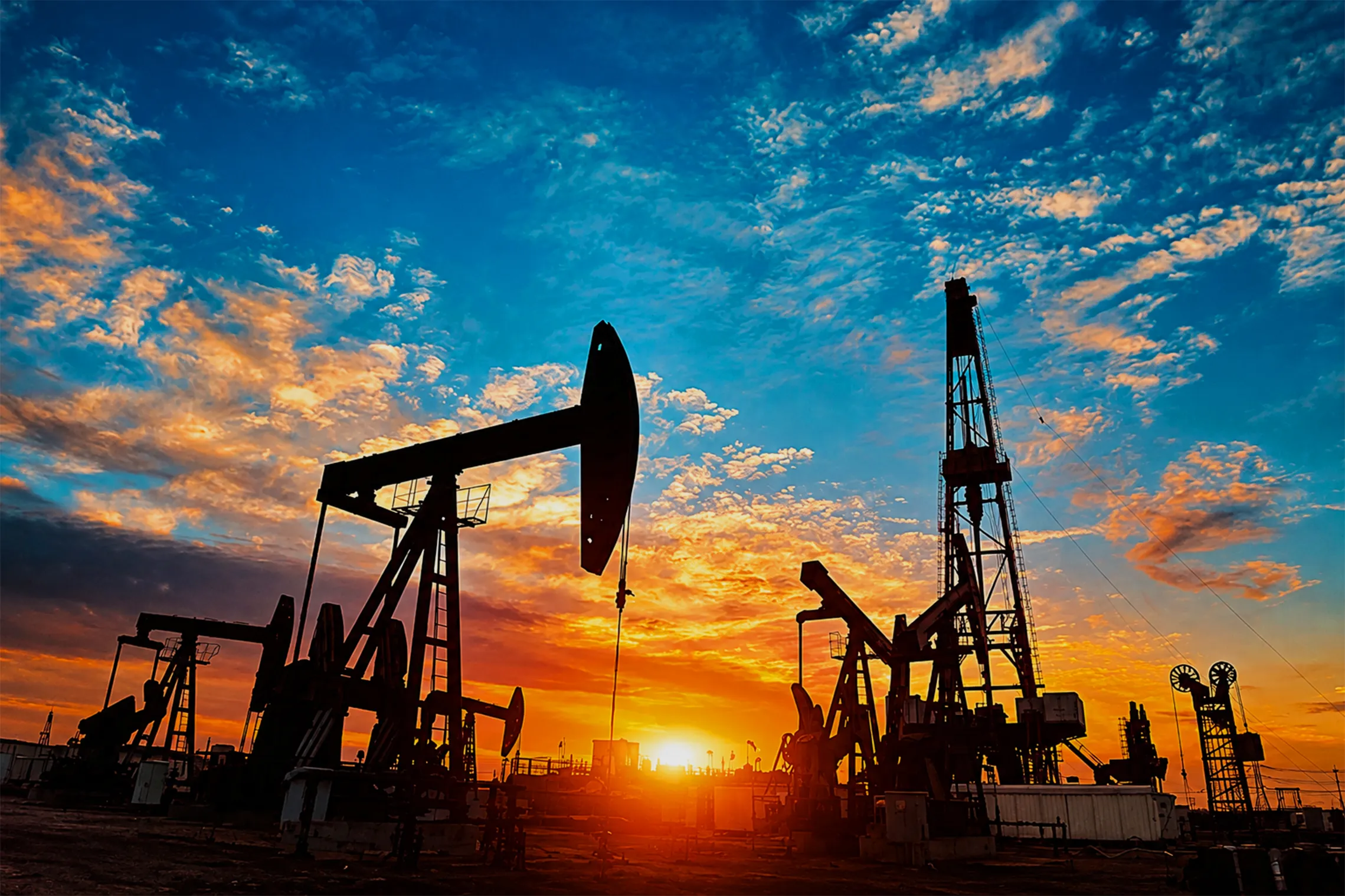 Oil pumps and drilling rigs silhouette at sunset